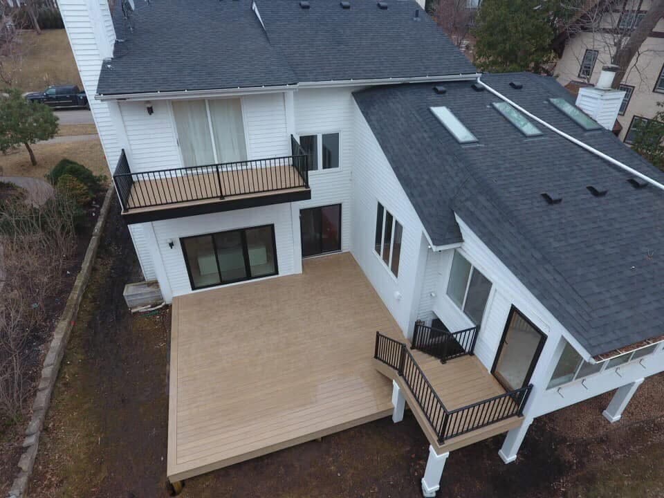 Multi-level deck on a white house with a balcony